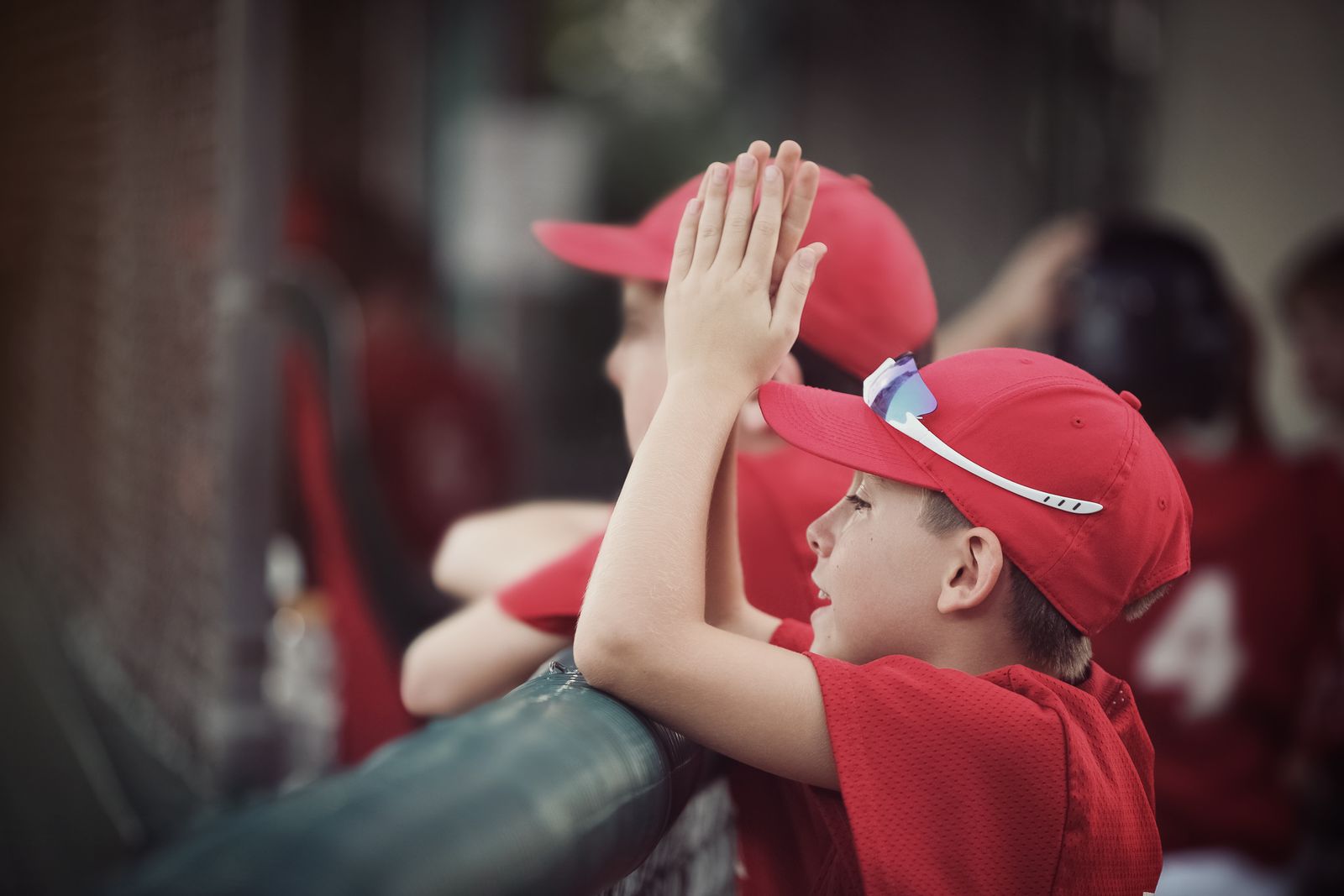 Young players in red caps cheering from the dugout