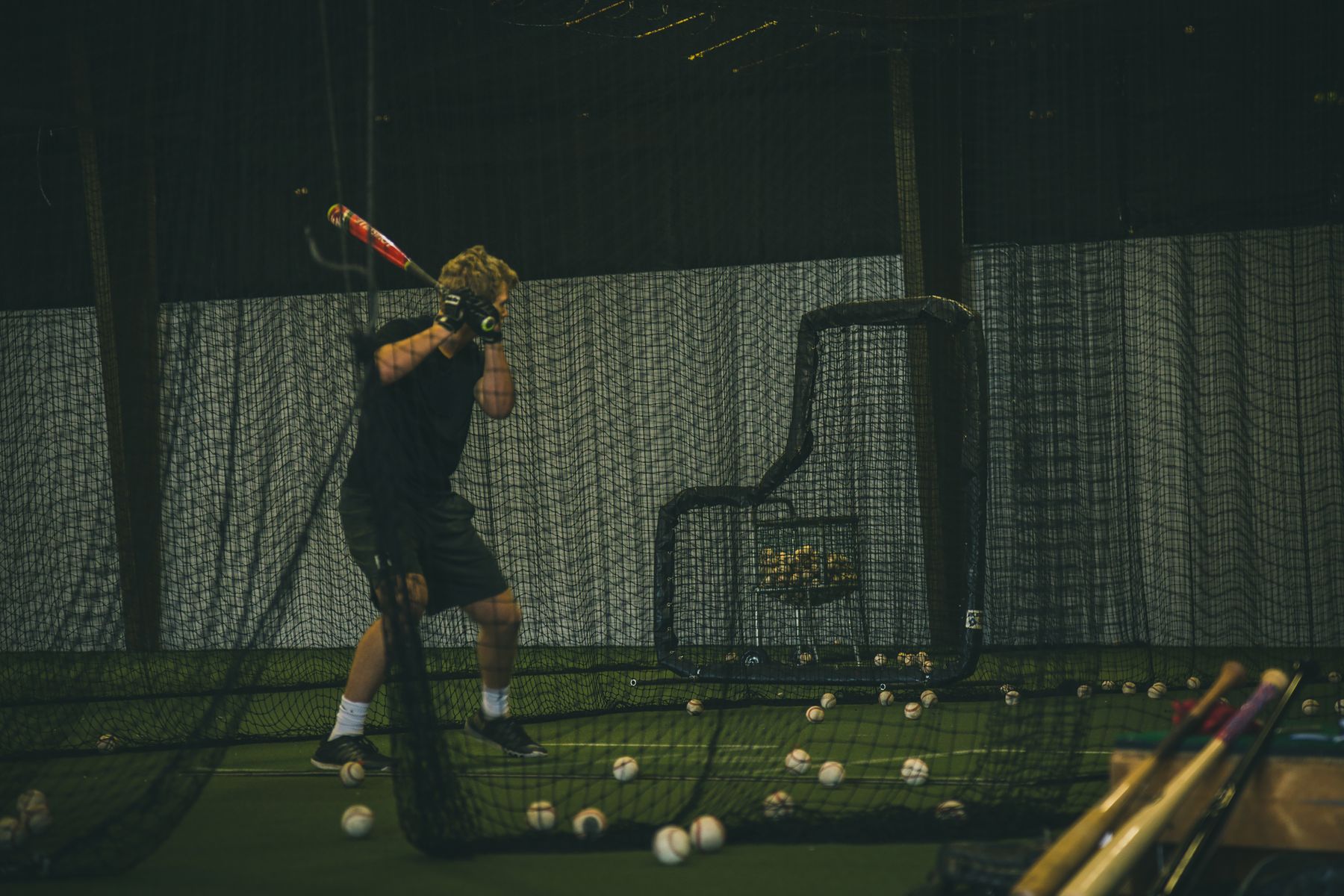 Hitter taking swings in an indoor batting cage