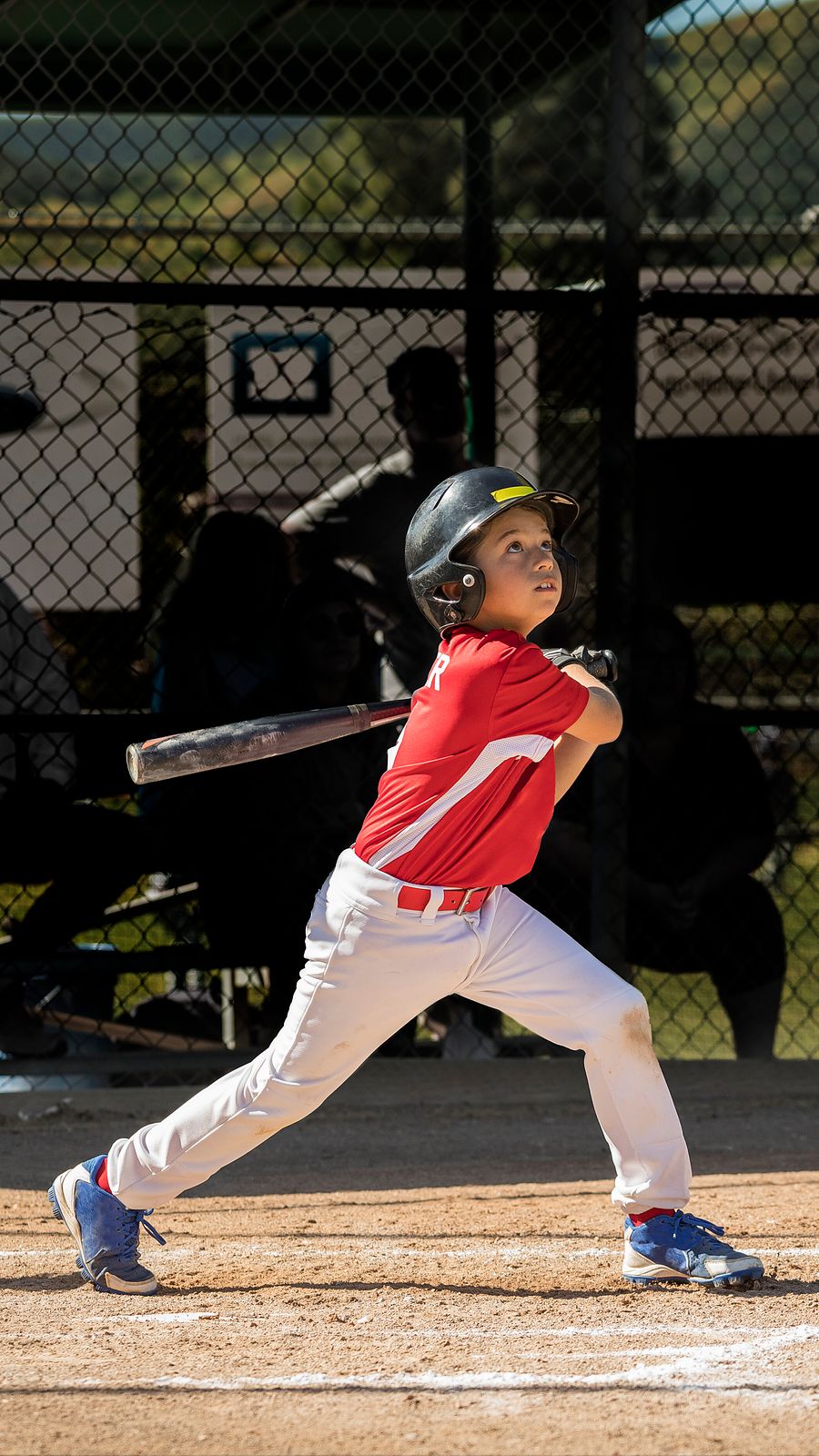 Young hitter in a red jersey following through on a swing